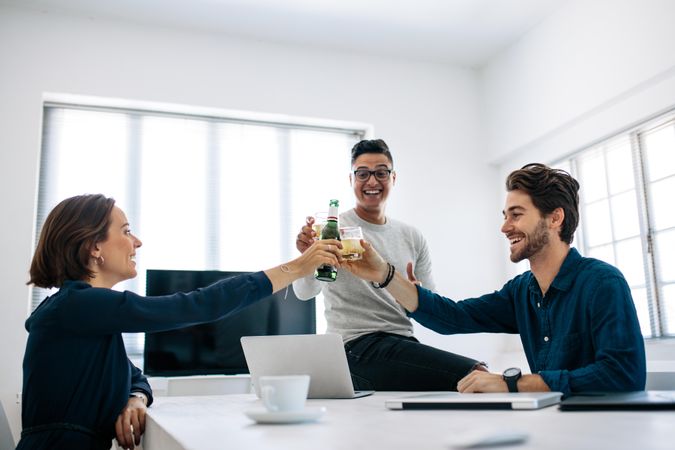Business people celebrating success by toasting drinks sitting in office