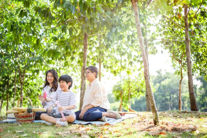 Asian boy blowing bubbles with his mother and grandmother looking on