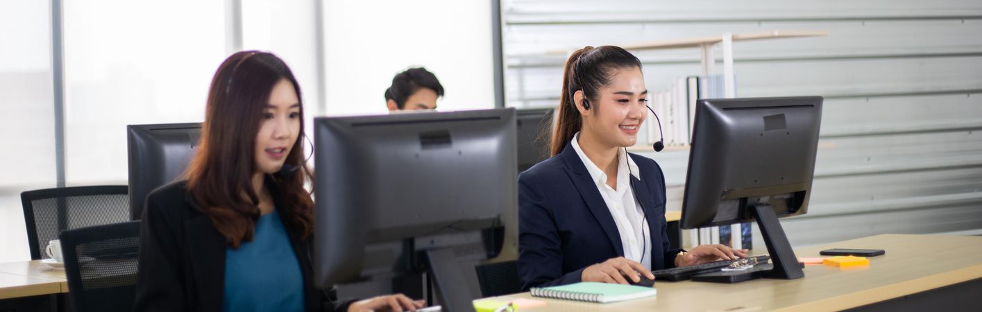 Business call center man and women with headset sitting in office desk using computer
