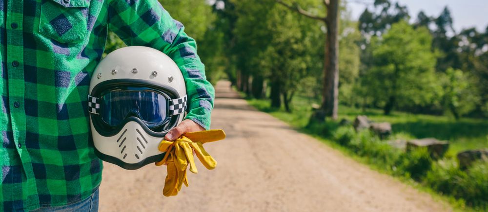 Man posing with motorcycle helmet and gloves