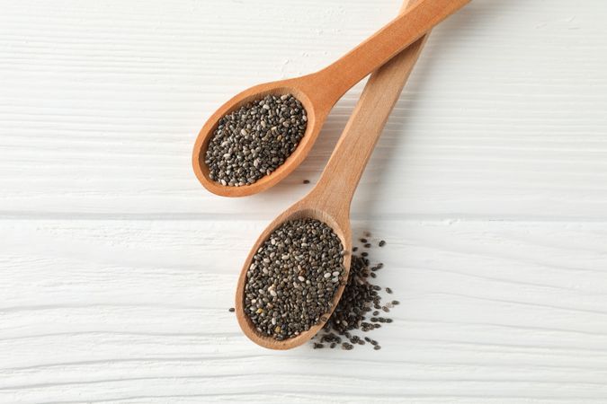 Chia seeds and wooden spoons on wooden background, copy space