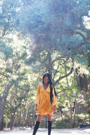 Fashionable woman in short yellow dress and tall black socks in the woods