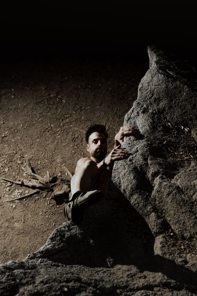 Man practicing rock climbing among large rocks in a forest