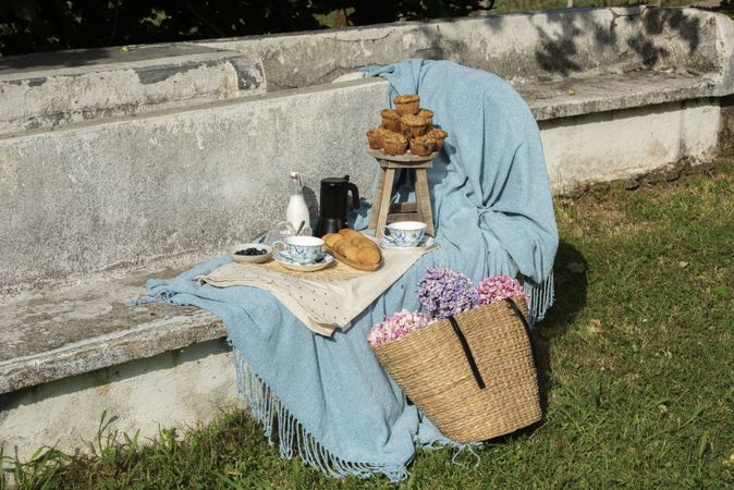 Delicious breakfast with tea and sweets on bench at garden