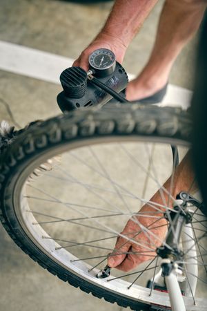 Anonymous man pumping up wheel of bicycle