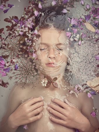 Boy lying underwater in bathtub with flowers