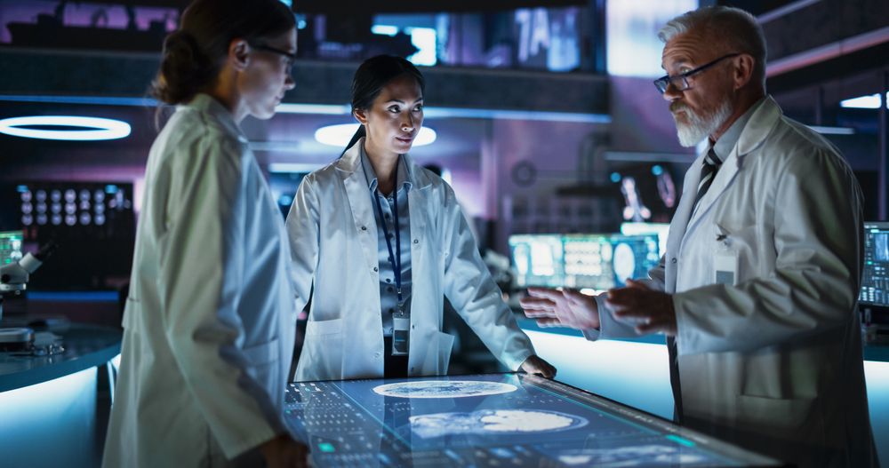 Modern Hospital Medical Research Center: Diverse Colleagues Gathered Around Interactive Touch Screen Table With CT Scans Of Brain On Display.