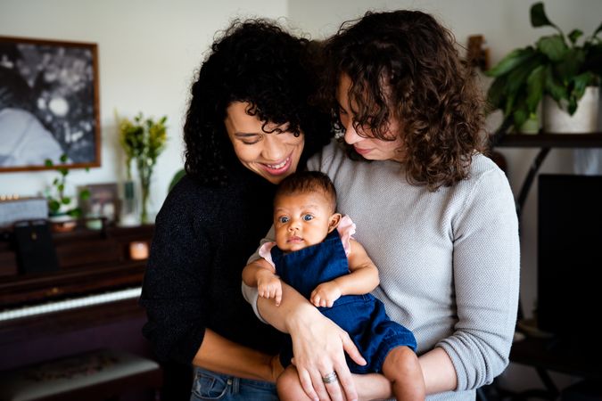 Two woman holding their newborn baby at home