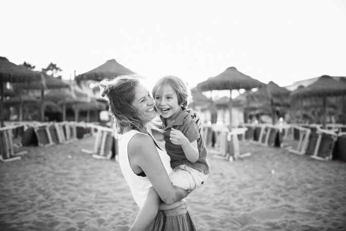 Woman with naughty boy on hands on beach