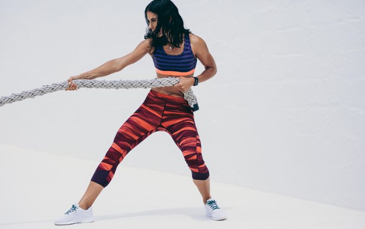 Fitness woman doing workout using a battle rope