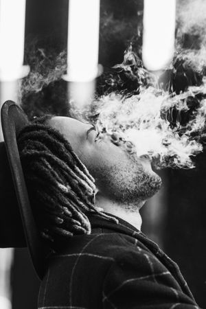 Black man exhaling cloud of smoke on street