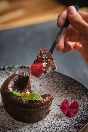 Unrecognizable person eating lava cake from plate