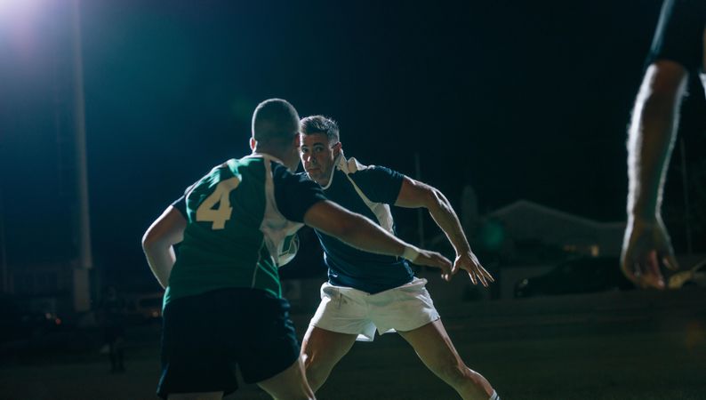 Rugby players fighting for ball in night match