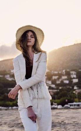 A long hair fashion model with a hat at the beach at sunset in a summer day