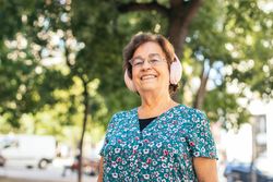 Mature woman walking down the street listening to music