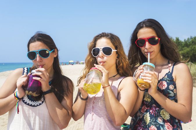 Group of happy young women toasting non alcoholic drinks on summer beach