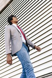 Man in gray blazer and blue denim jeans standing beside gray roll up door