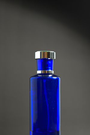 Blue perfume bottle on grey background with copy space