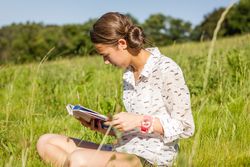 young student reading a book in the park