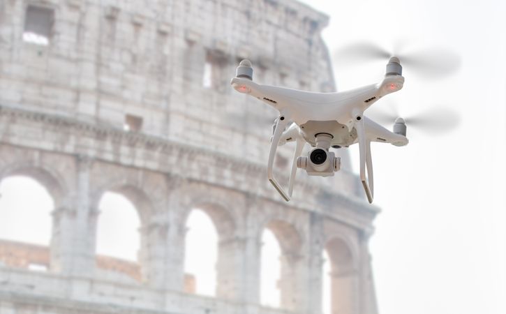 Unmanned Aircraft System Quadcopter Drone UAV In The Air Near The Colosseum In Rome.