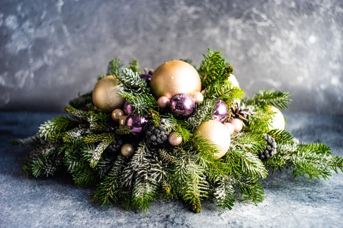 Side view of purple and gold holiday baubles in pine centerpiece