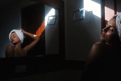 woman with towel on head against mirror in bathroom