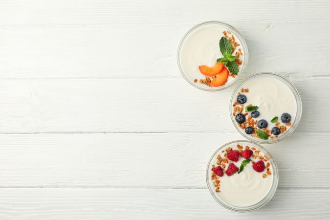 Flat lay composition with yogurt desserts and ingredients on wooden background