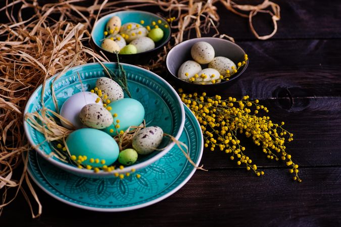 Easter holiday card with bowls of decorative eggs with straw and branches