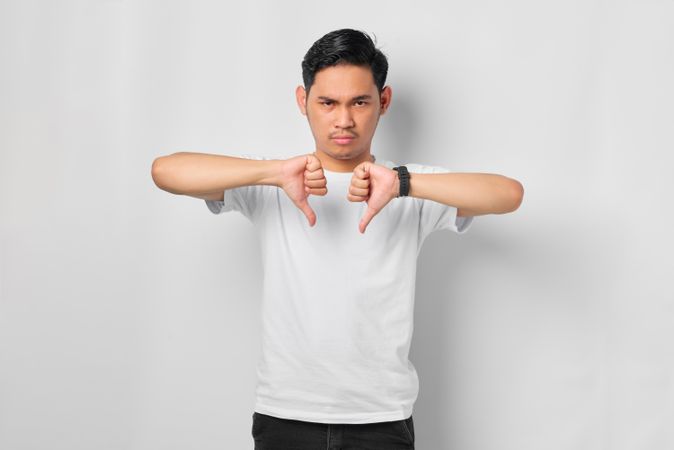 Asian male in grey studio with two thumbs down