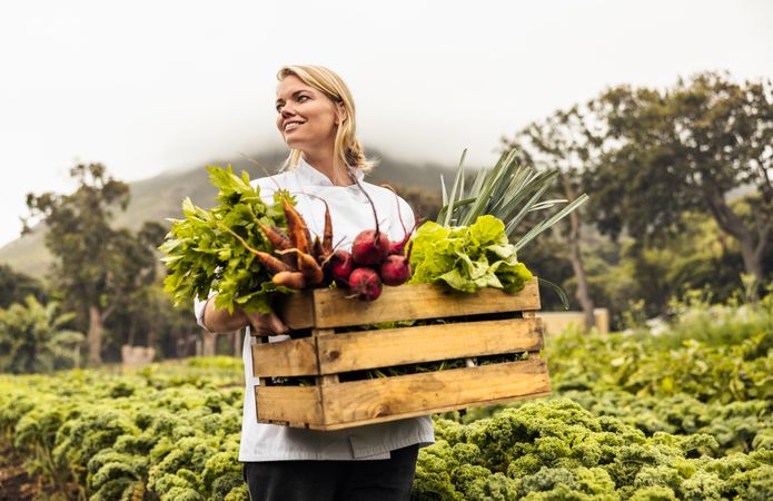 Self-sustainable chef standing in an agricultural field with a variety of fresh produce
