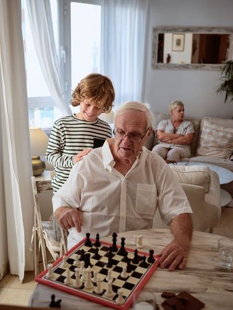 Grandson looking at grandfather playing chess
