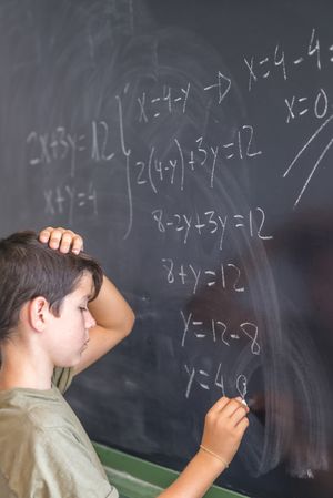 Teenager writing equation at chalkboard