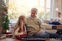 Little girl and grandfather by christmas tree with tablet pc 5kRv86