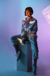 Trendy female sitting on cuboid
