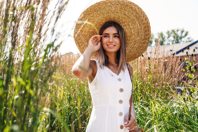 Calm happy woman in a field outside in sundress and sunhat