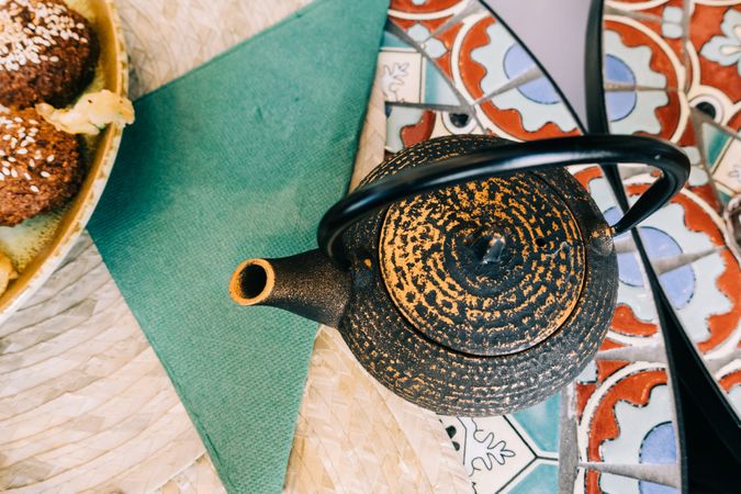 Teapot near plate with delicious food on table