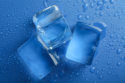 Looking down at top view of four melting ice cubed on blue table, close up