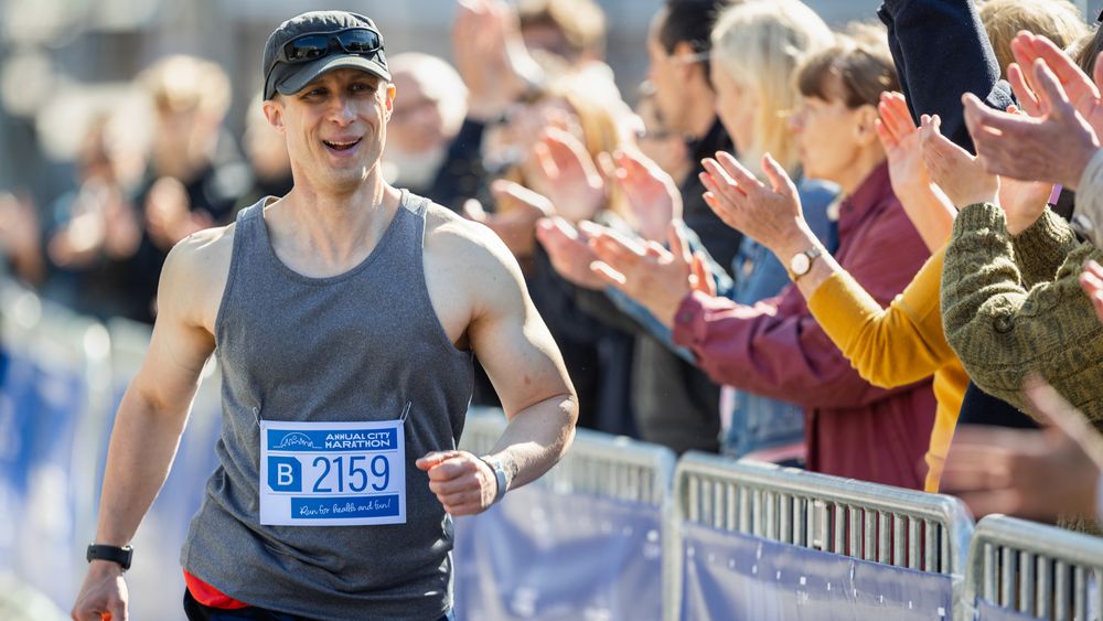 Portrait of Smiling Man Running in a City Marathon, Waving at the Supportive Audience.