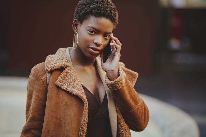 Stylish Black woman talking on smartphone on street