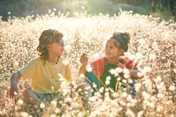 Happy siblings sitting on meadow full of flowers