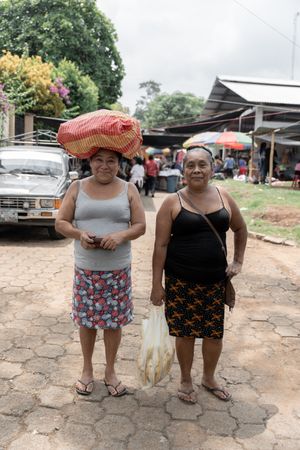 Two Hispanic women are posing holding groceries on the head