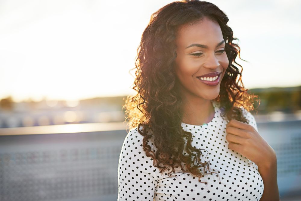 Black woman on bright rooftop with thoughtful expression