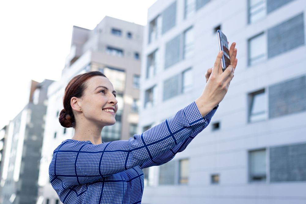 Smiling businesswoman taking selfie on street