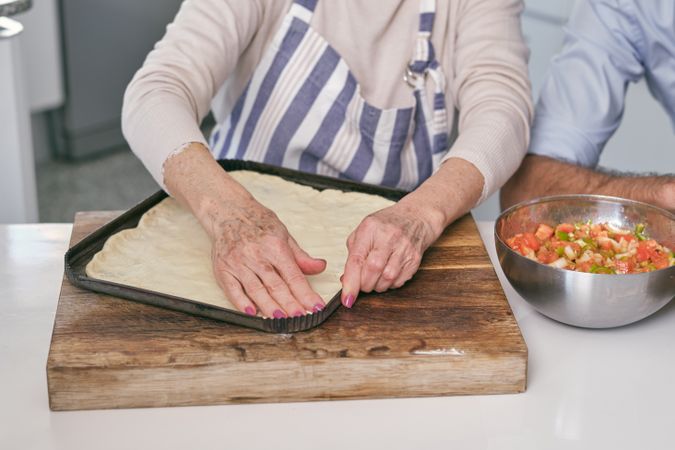 Anonymous woman preparing dough on baking pan