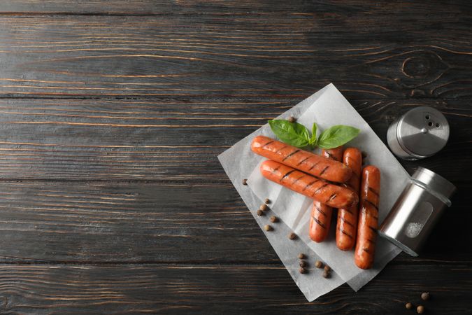 Grilled sausages or hot dogs with capers and basil, top view with copy space
