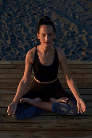 Tranquil Hispanic woman in lotus pose on shore