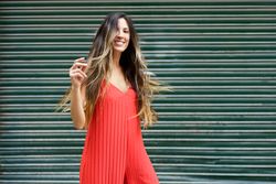 A Joyful Woman Dressed in a Vibrant Red Dress Posing Gracefully Against a Lively Green Backdrop
