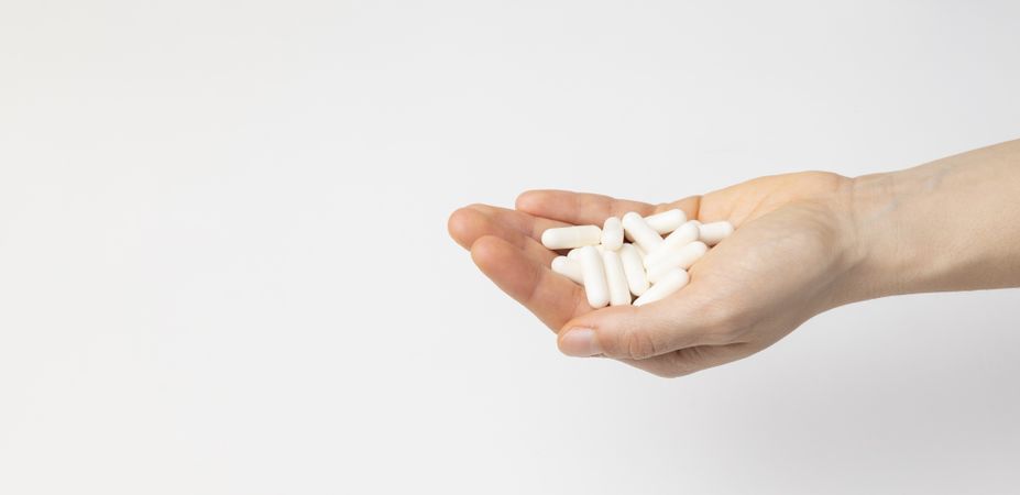 The hand of a woman holds a handful of vitamin D3 capsules, food supplement