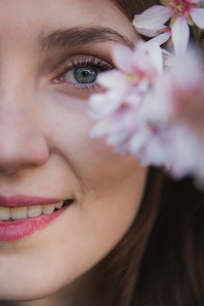Young woman near tree twig with flowers