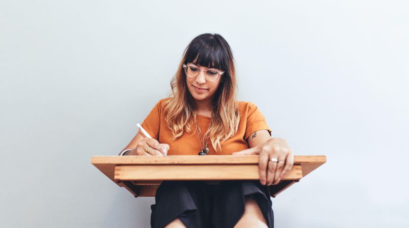 Portrait of a woman sitting on floor with a drawing pad making a sketch